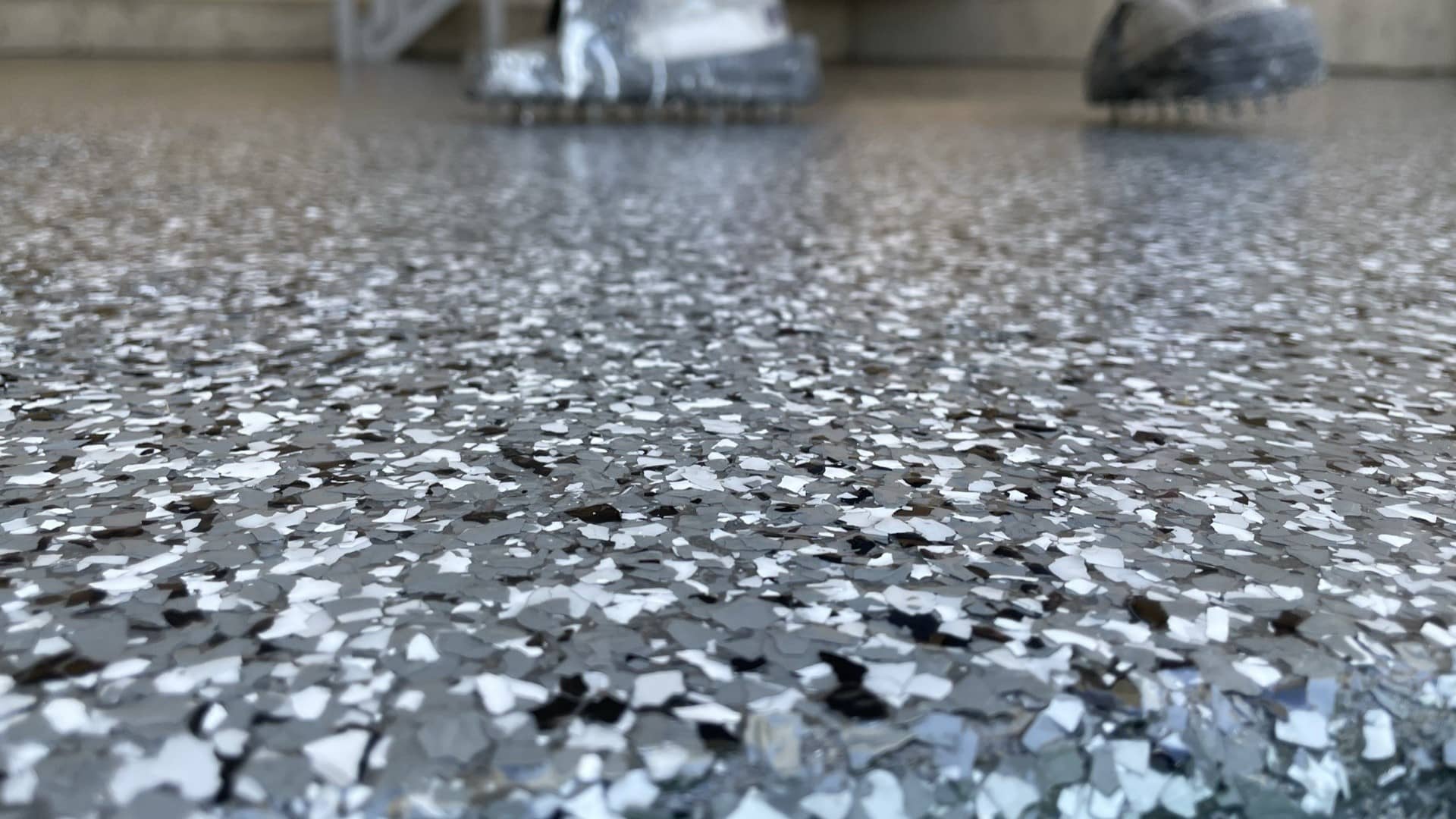 Close-up of a gray, white and black flake epoxy floor under a glossy clear topcoat