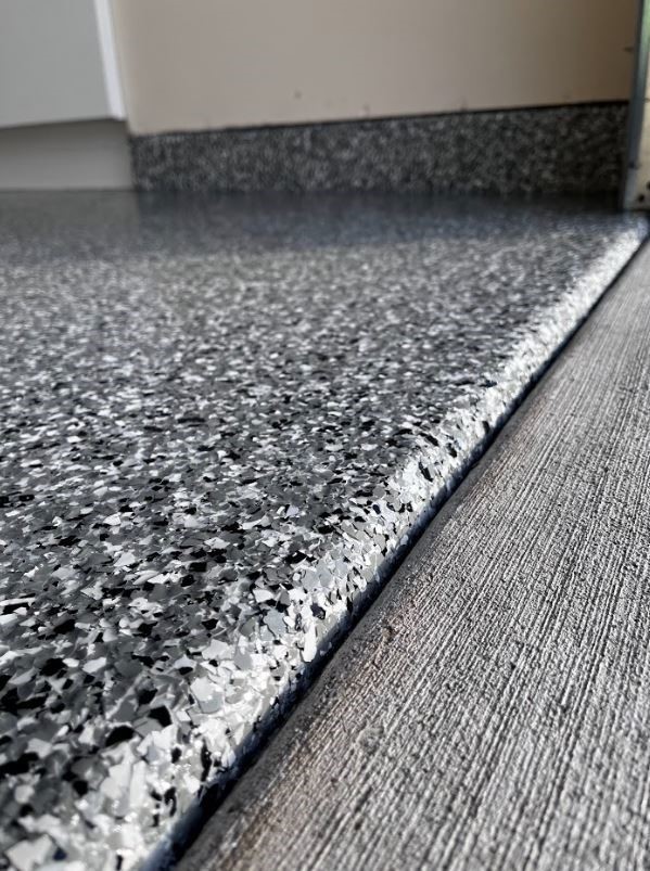 Clean finished edge of a gray flake epoxy garage floor coating
