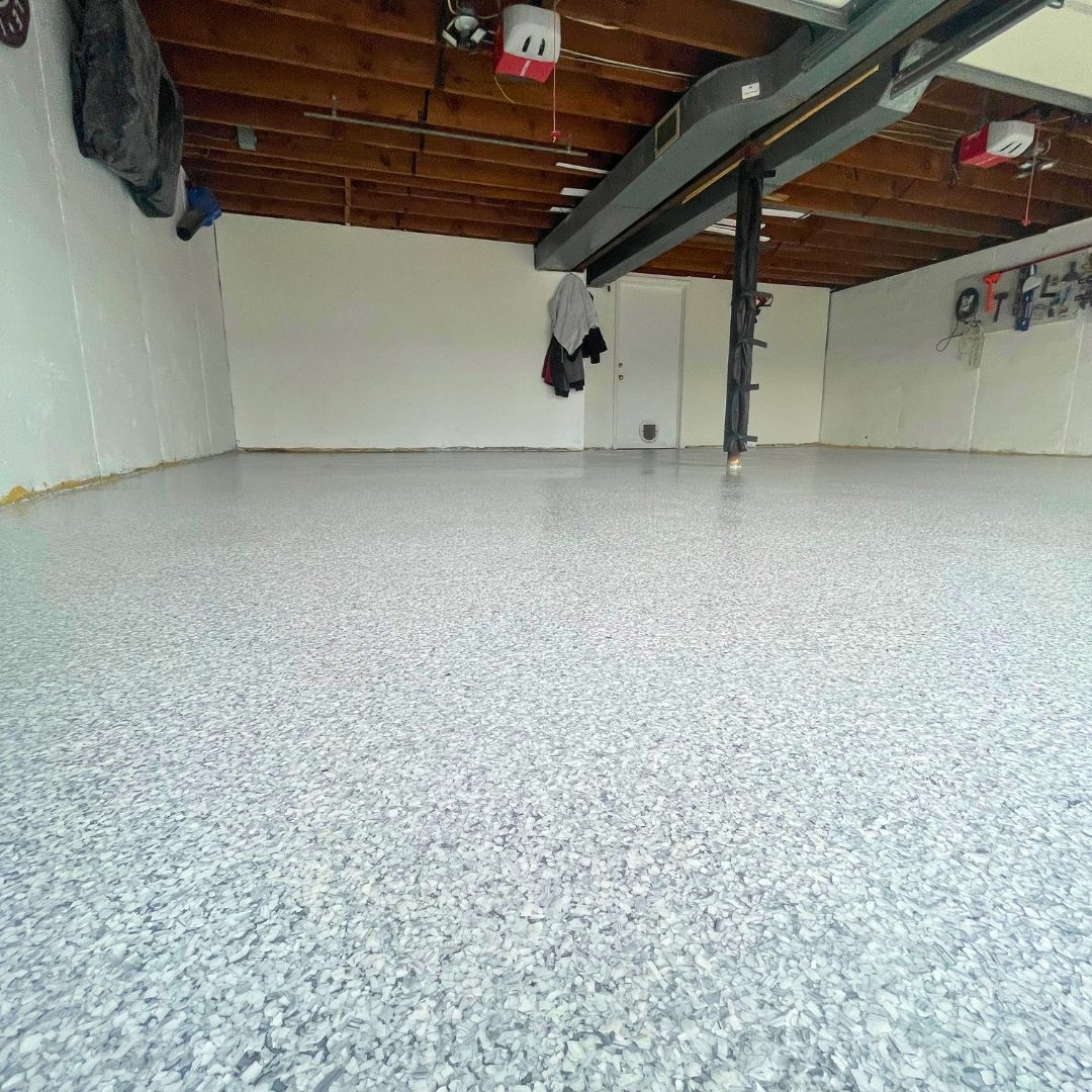 Close-up of a gray and white Schist flake epoxy garage floor under a gloss polyaspartic topcoat