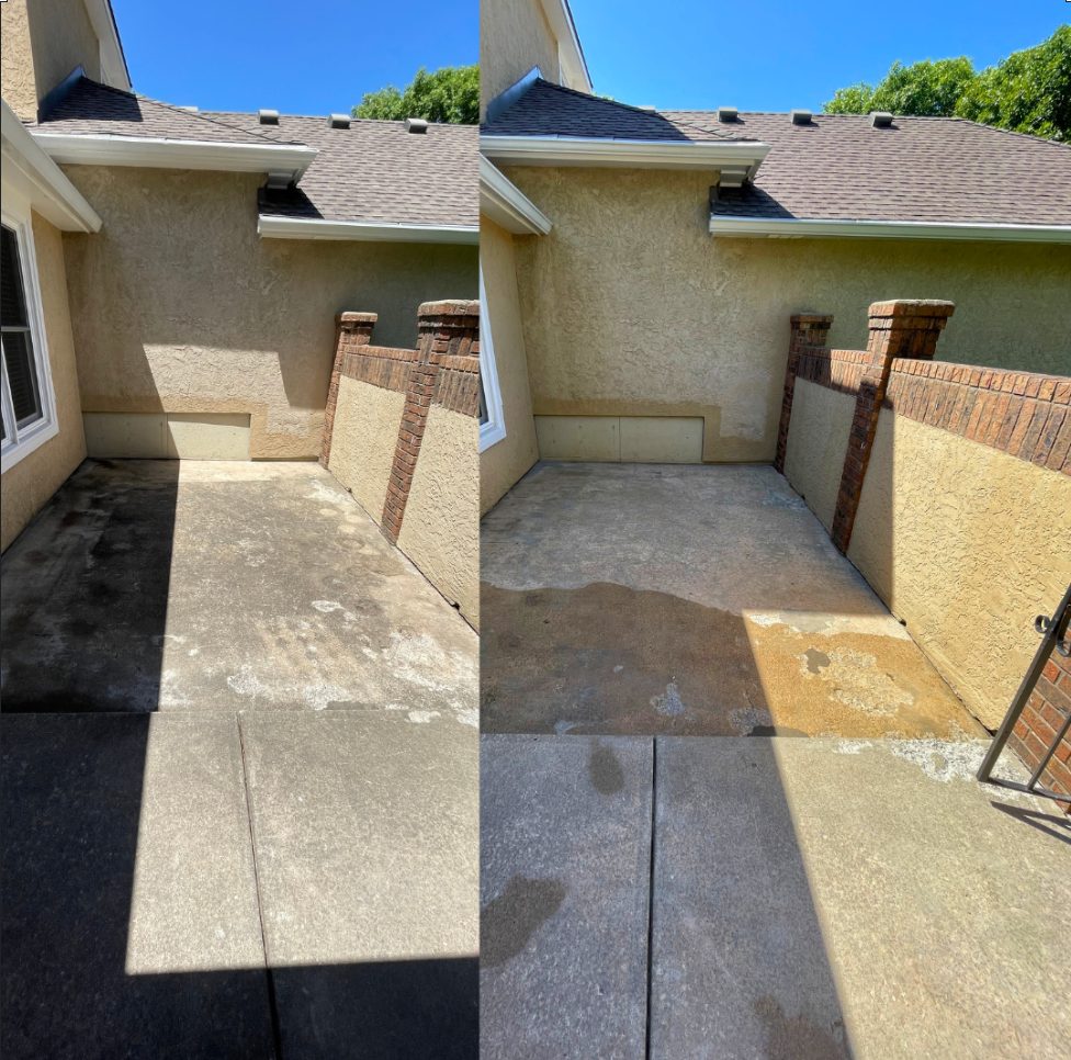 Before and after pressure washing of a concrete patio enclosed by stucco walls and brick pillars in Olathe, KS, heavy dark staining removed on the right
