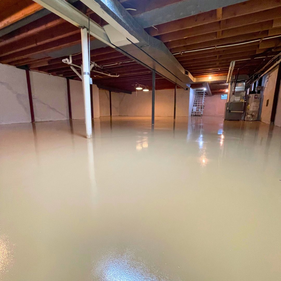 Finished sand tan solid epoxy basement floor in Overland Park, KS with a smooth glossy surface reflecting the support columns